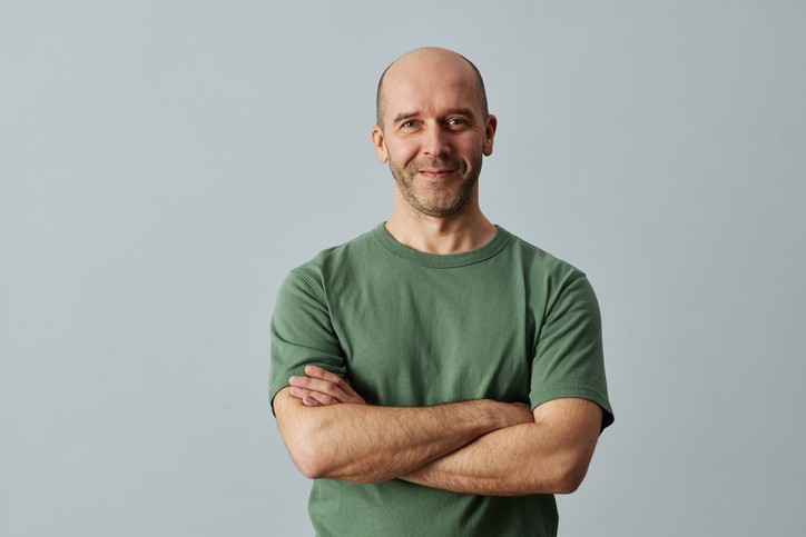 Bald man smiling at camera standing with arms crossed john