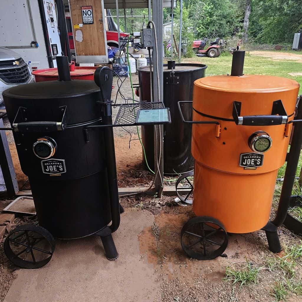 bundle_Bronco_2 Black and orange insulated outdoor smokers on wheels, ideal for barbeque competitions and outdoor cooking.