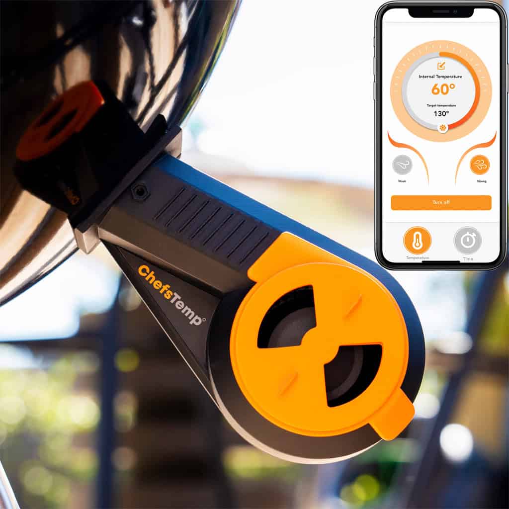 Wireless grilling thermometer attached to a barbecue, with a smartphone displaying temperature control for precise cooking.