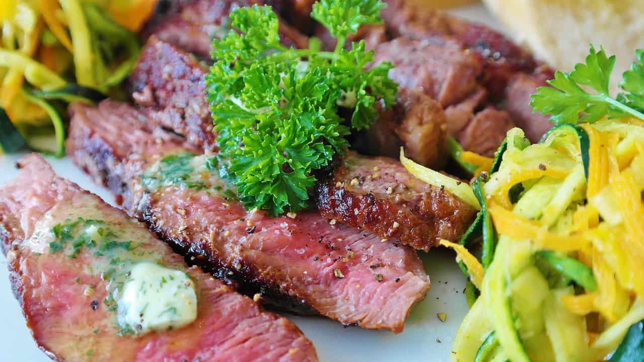 Delicious grilled steak slices topped with parsley, served alongside a vibrant zucchini and yellow squash salad.