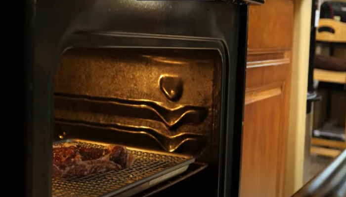 Oven with baked meat inside, professional kitchen equipment, high-temperature cooking appliance.
