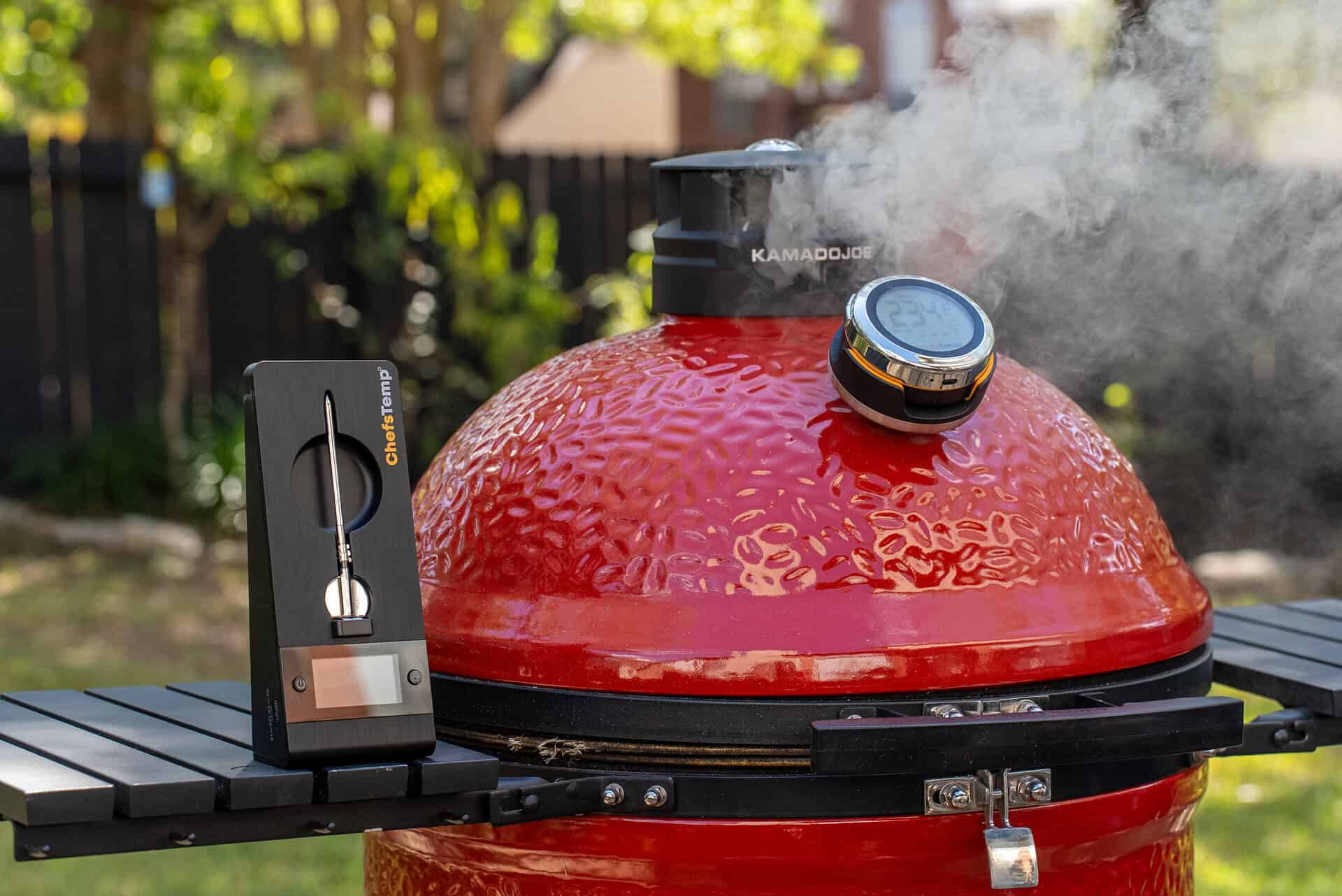 Wireless thermometer on a red ceramic grill with lock-in temperature display for perfect grilling.