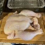 Raw whole chicken on cutting board for precise temperature cooking.