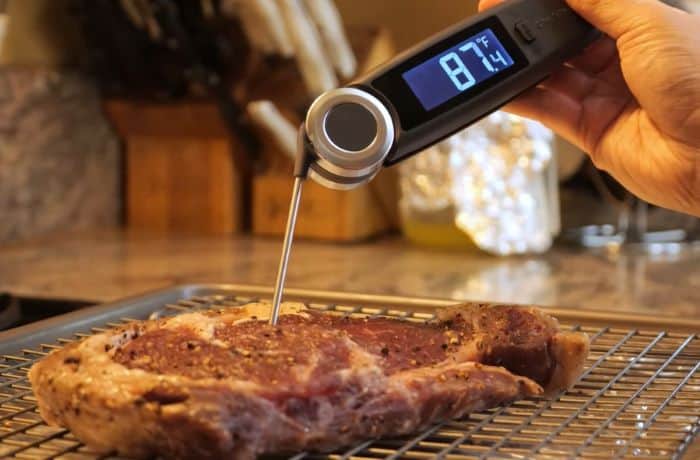 Digital meat thermometer testing cooked steak for perfect doneness.