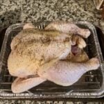Raw whole chicken on a baking tray ready for cooking.