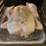 Digital food thermometer on cooked turkey in roasting pan for precise temperature monitoring.