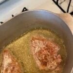 Juicy meat patties frying in hot oil on stovetop for cooking.