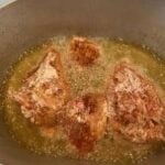Digital thermometer cooking meat in hot oil; food thermometer for precise cooking.