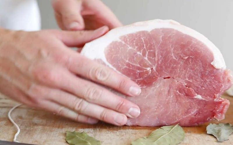 Fresh raw pork meat on cutting board for safe cooking and food preparation.