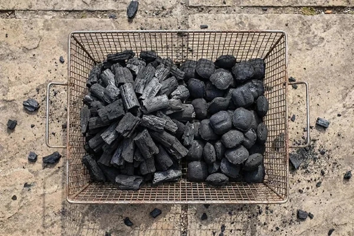 fresh charcoal arranged in one concentrated hot zone and one wider, thinner zone beside an unbranded charcoal basket, without packaging, branding, or identifiable person.